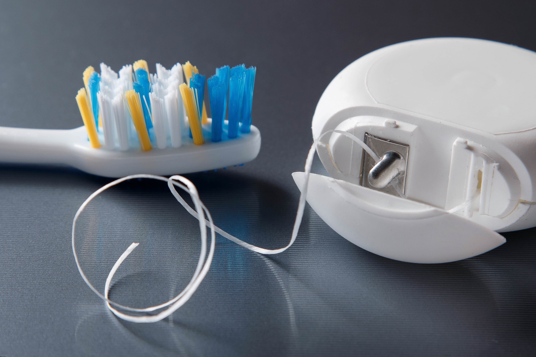 close up of tooth floss and tooth brush with blue background