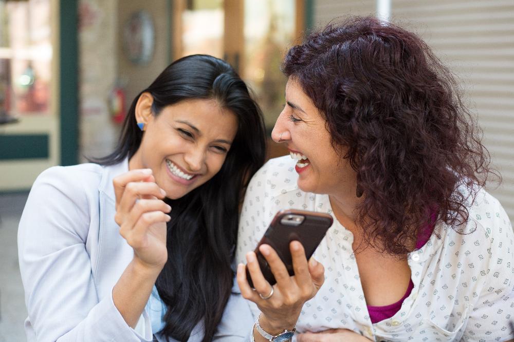 two women looking at phone | teeth whitening marysville wa