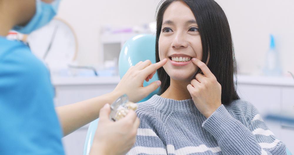 woman pointing at teeth in chair | teeth whitening marysville wa