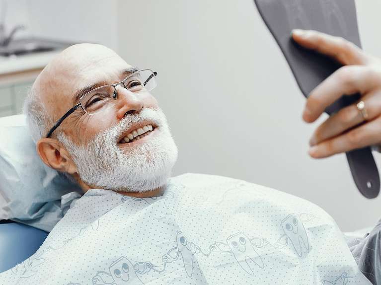 A smiling man looking at his teeth in the dentist's office
